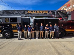 Los alumnos de la High Road School de York posan juntos junto a un camión con escalera del cuerpo de bomberos Alliance Fire Rescue.