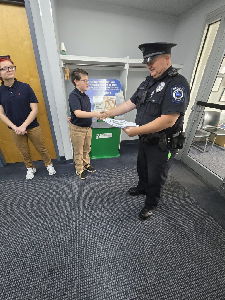 Un alumno entrega una carta de agradecimiento a un agente de la Policía Regional del condado de York durante las actividades conmemorativas del 11-S organizadas por el colegio.