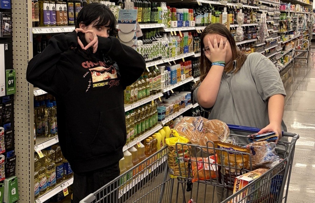 Two High Road School of Nashville students stand beside a grocery cart filled with items in a Kroger store aisle.