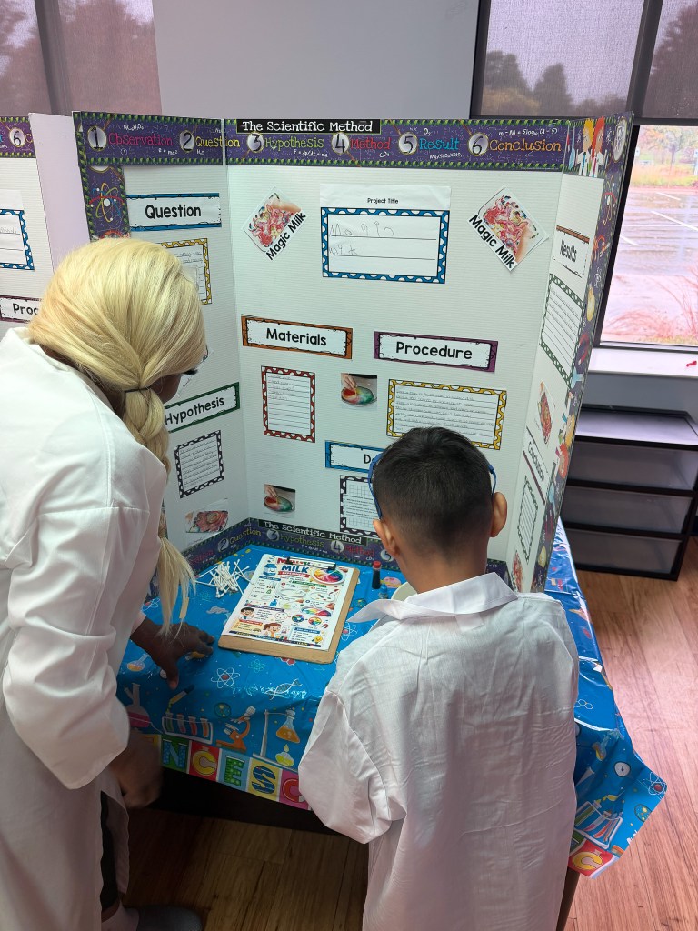 Un alumno y un adulto de la escuela High Road de Hoffman Estates observan una exposición sobre un experimento científico con «leche mágica» durante la feria de ciencias de la escuela.