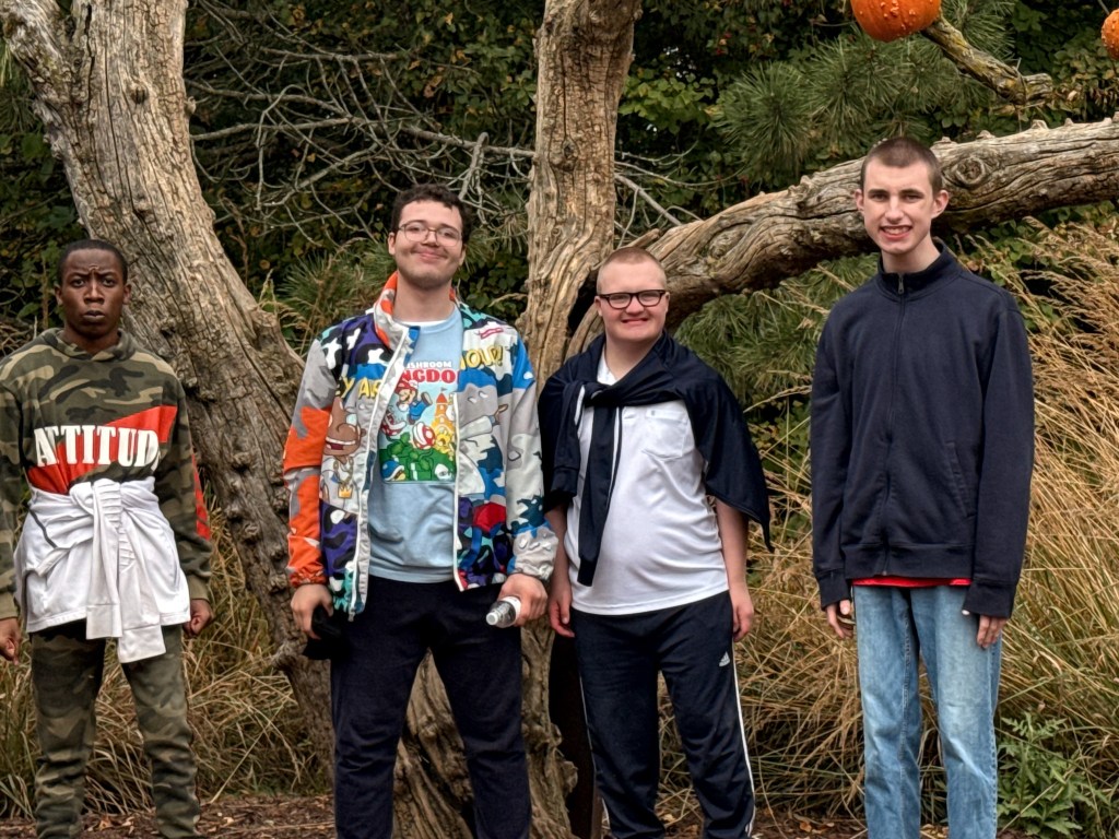 Cuatro alumnos están juntos junto a un árbol grande durante una excursión a la granja Lincoln Ridge.