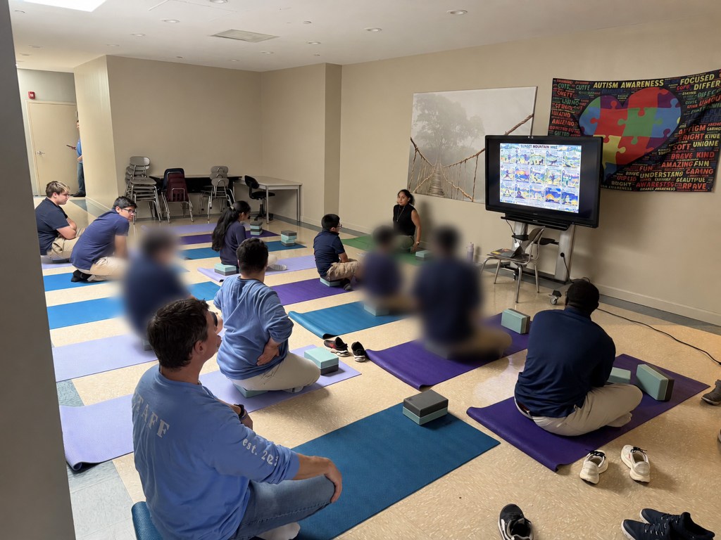 Students at High Road School of Anne Arundel County follow a guided yoga lesson displayed on a classroom screen.
