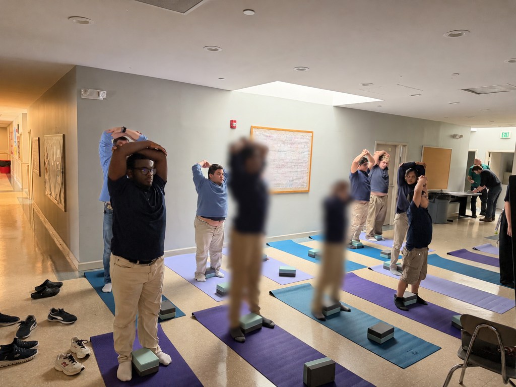 Students at High Road School of Anne Arundel County practice standing stretches during a Friday yoga session.