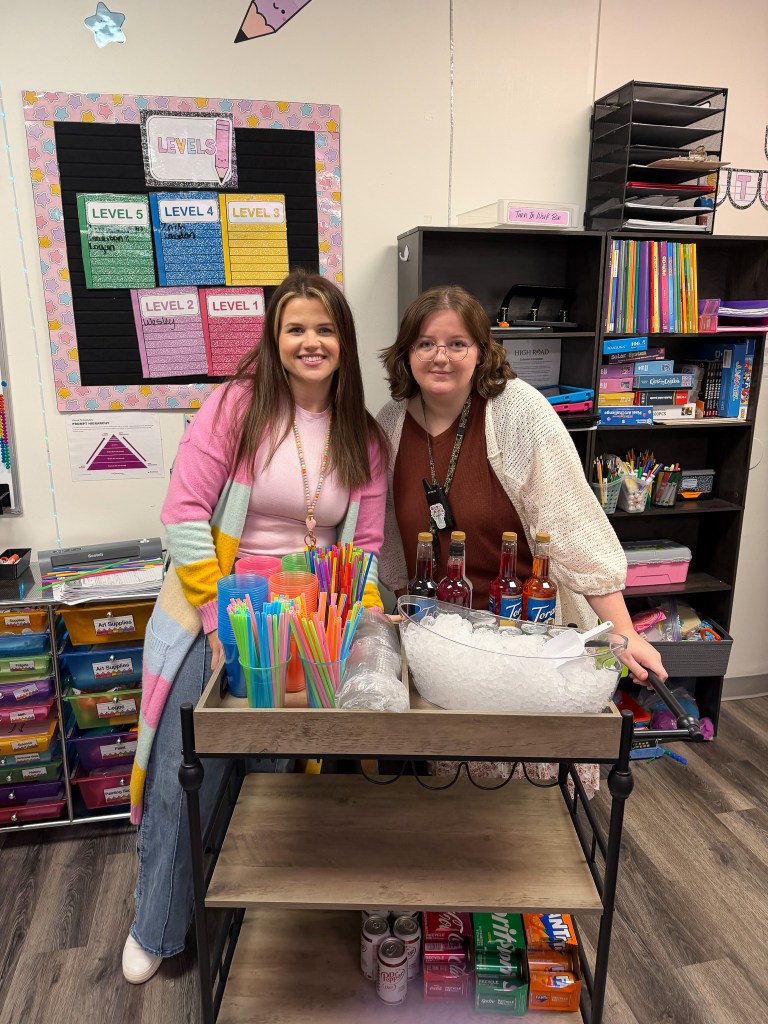 Two High Road School of Wright City staff members standing behind the Pick-Me-Up Cart with drink supplies and refreshments.