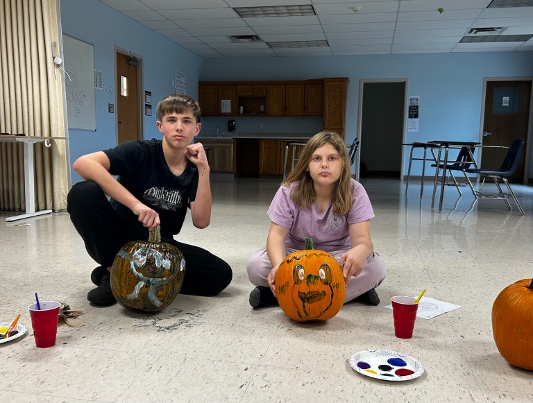 Dos alumnos de la escuela High Road School del condado de Cole posan junto a sus calabazas pintadas durante una actividad otoñal.