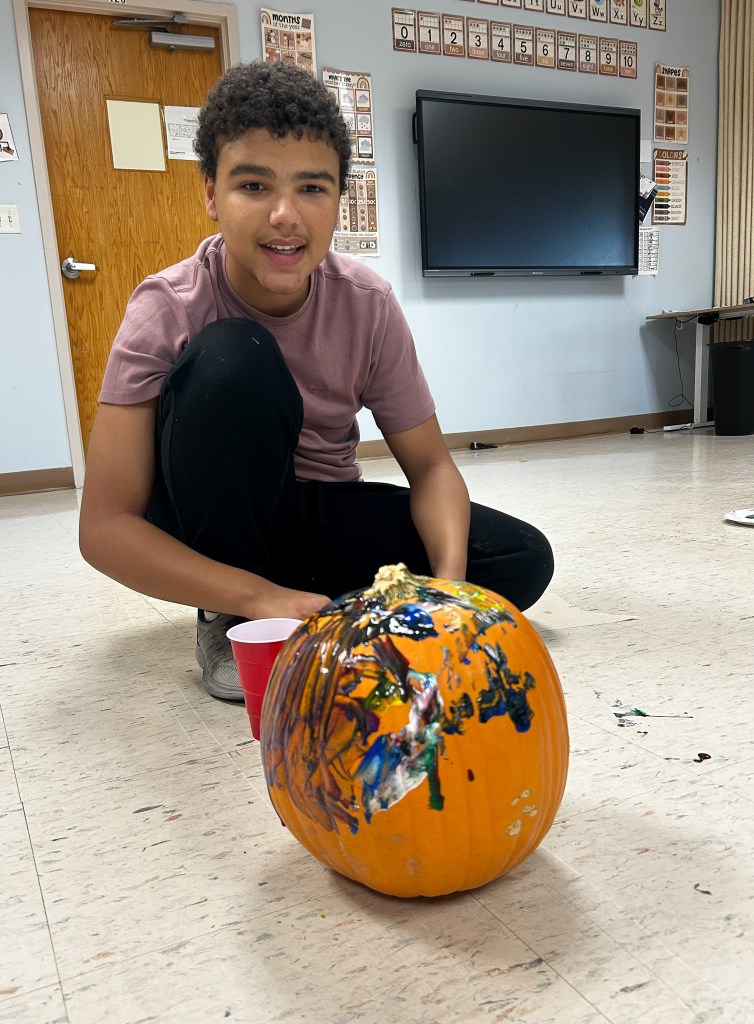 Un alumno de la escuela High Road School del condado de Cole pinta una calabaza durante una actividad escolar.
