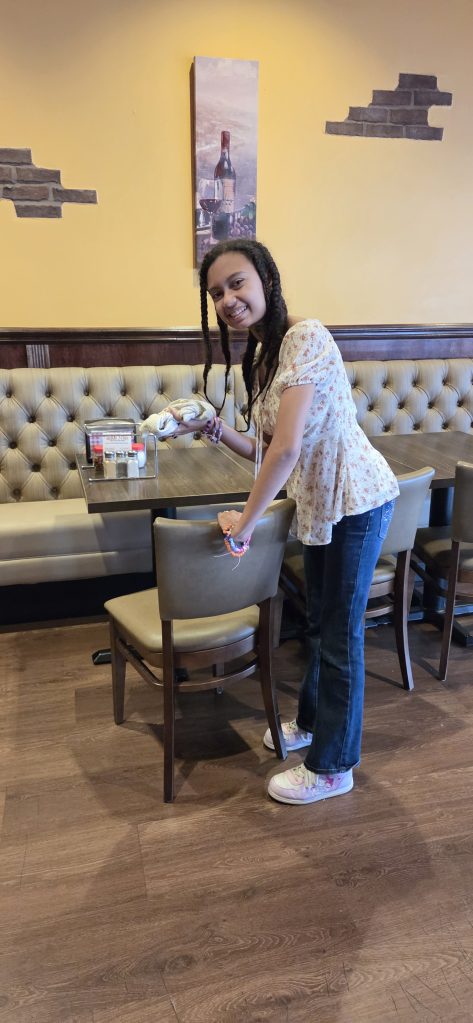 Sierra School of Gilbert student smiles while cleaning a table at Sal's Gilbert Pizza.