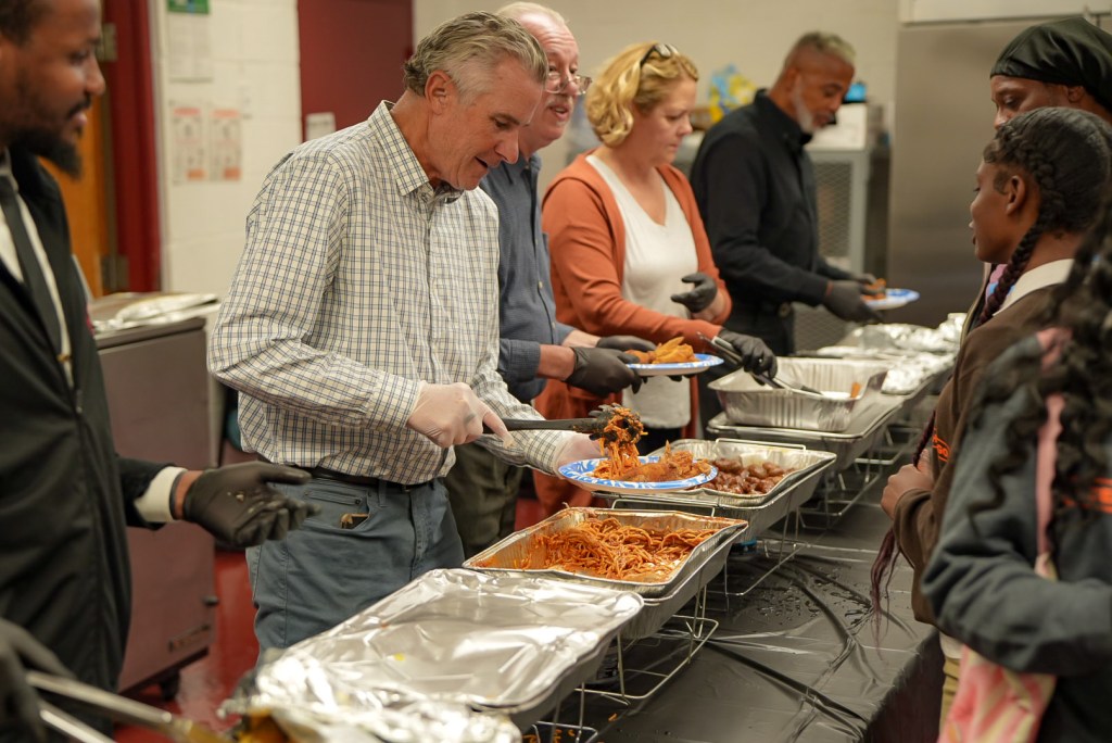 School leaders serving food to students and families during the Excel Roseland event.